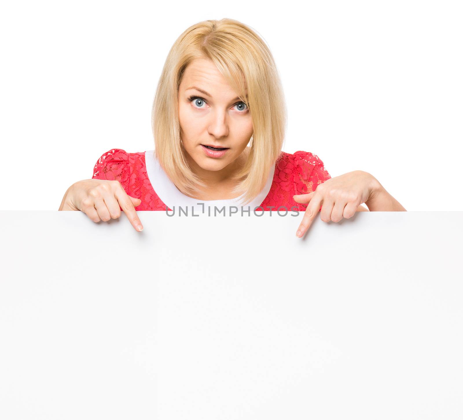 Young woman with surprised eyes peeking out from behind billboard paper poster. Businesswoman holding big white banner, isolated on white background.