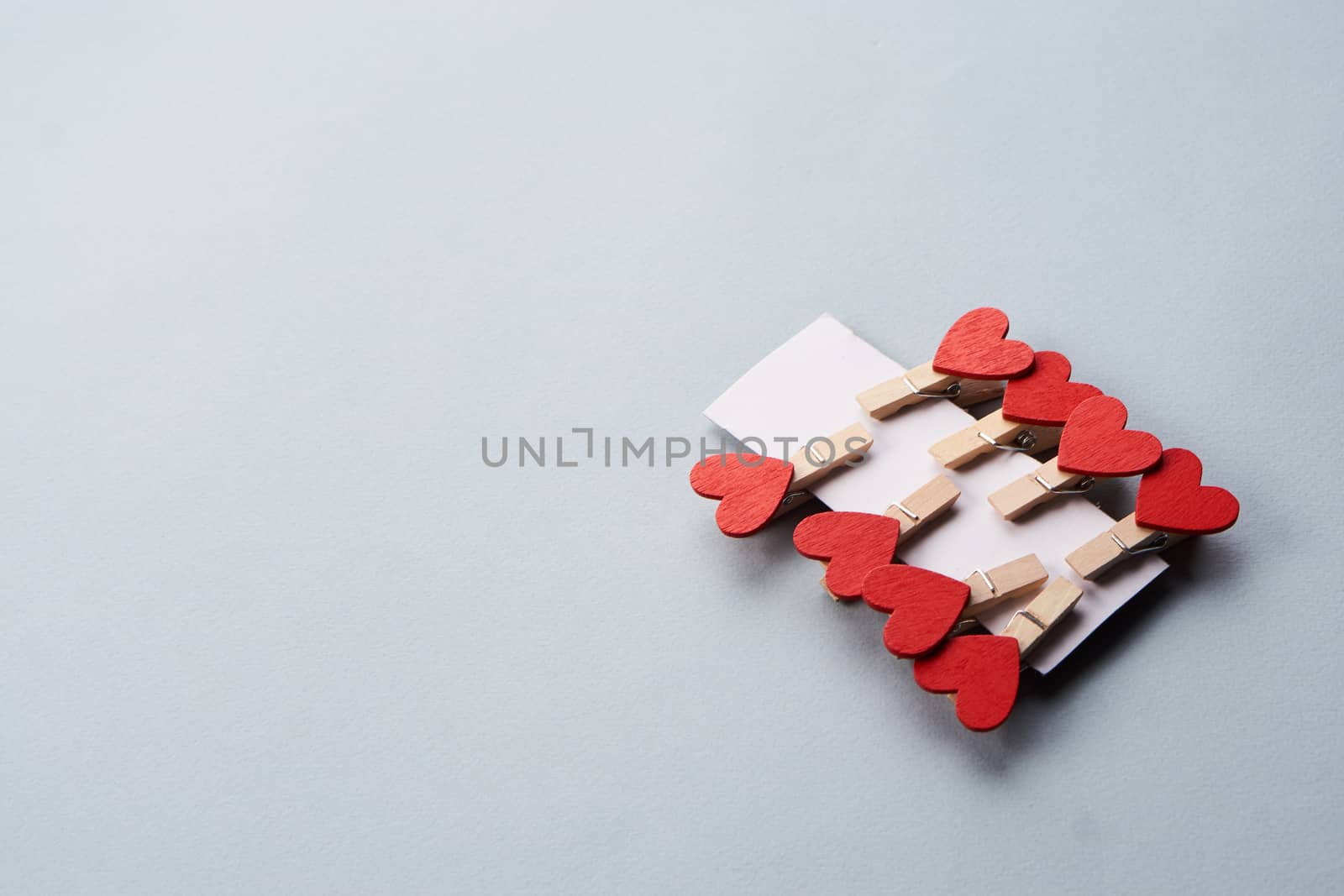 clothespins with hearts on a gray background and a sheet of cardboard. High quality photo