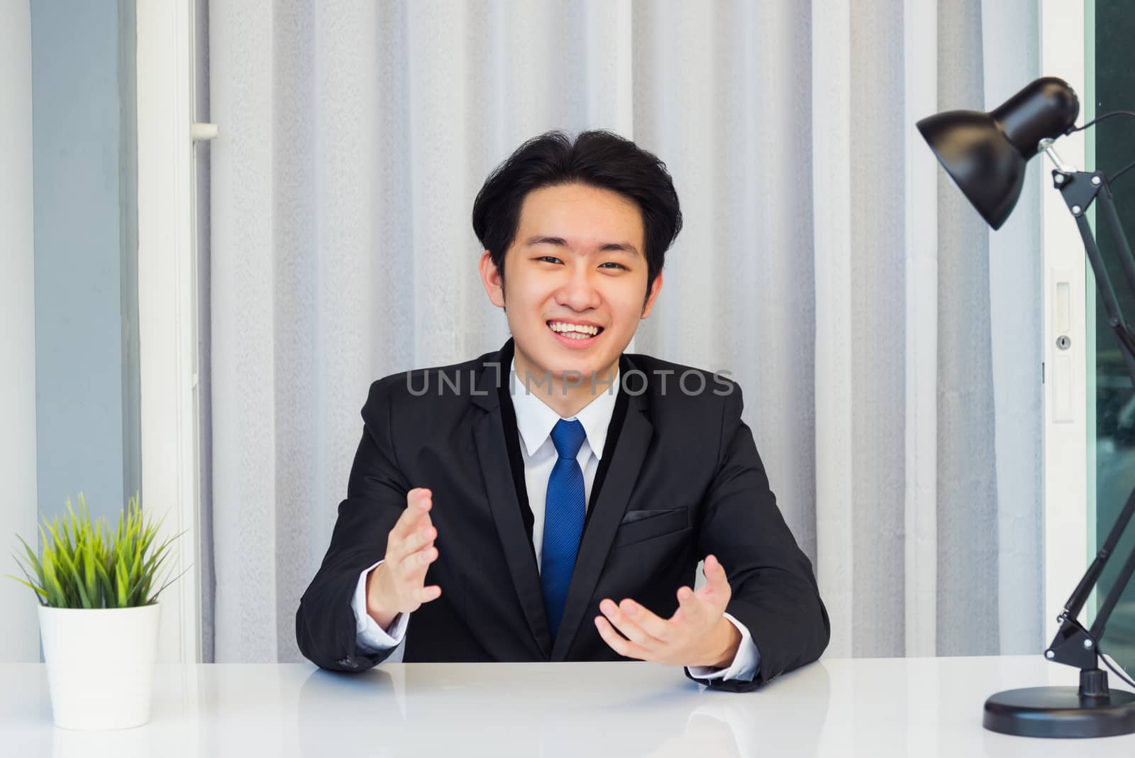 Work from home, Close up face of Asian young businessman video conference call or facetime he looking to camera raises hands to explain about his job to team on a desk at the home office