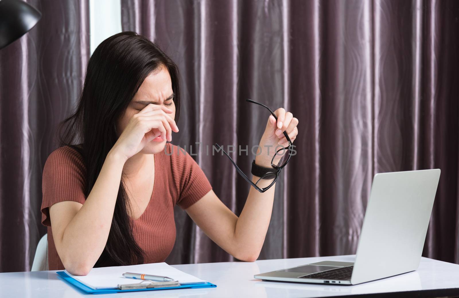 Work from home, Fatigued or strain Asian business young beautiful woman sits on desk workspace feeling tired stressed hold his nose close eyes after see screen long time of laptop computer at office