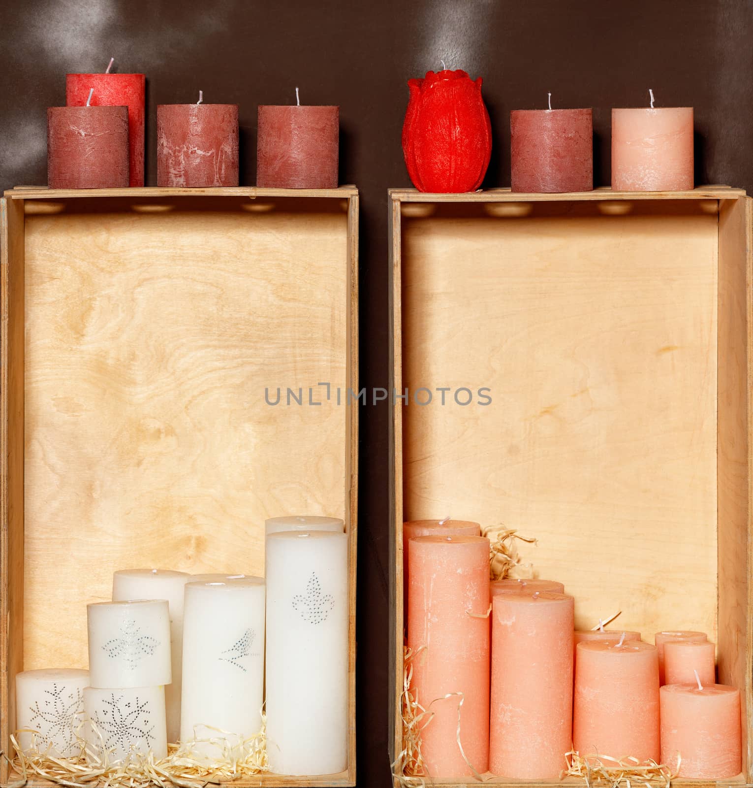 Thick New Years Christmas candles of white, red and pink colors stand as in a frame, in old wooden gift boxes, before Christmas, place for text.