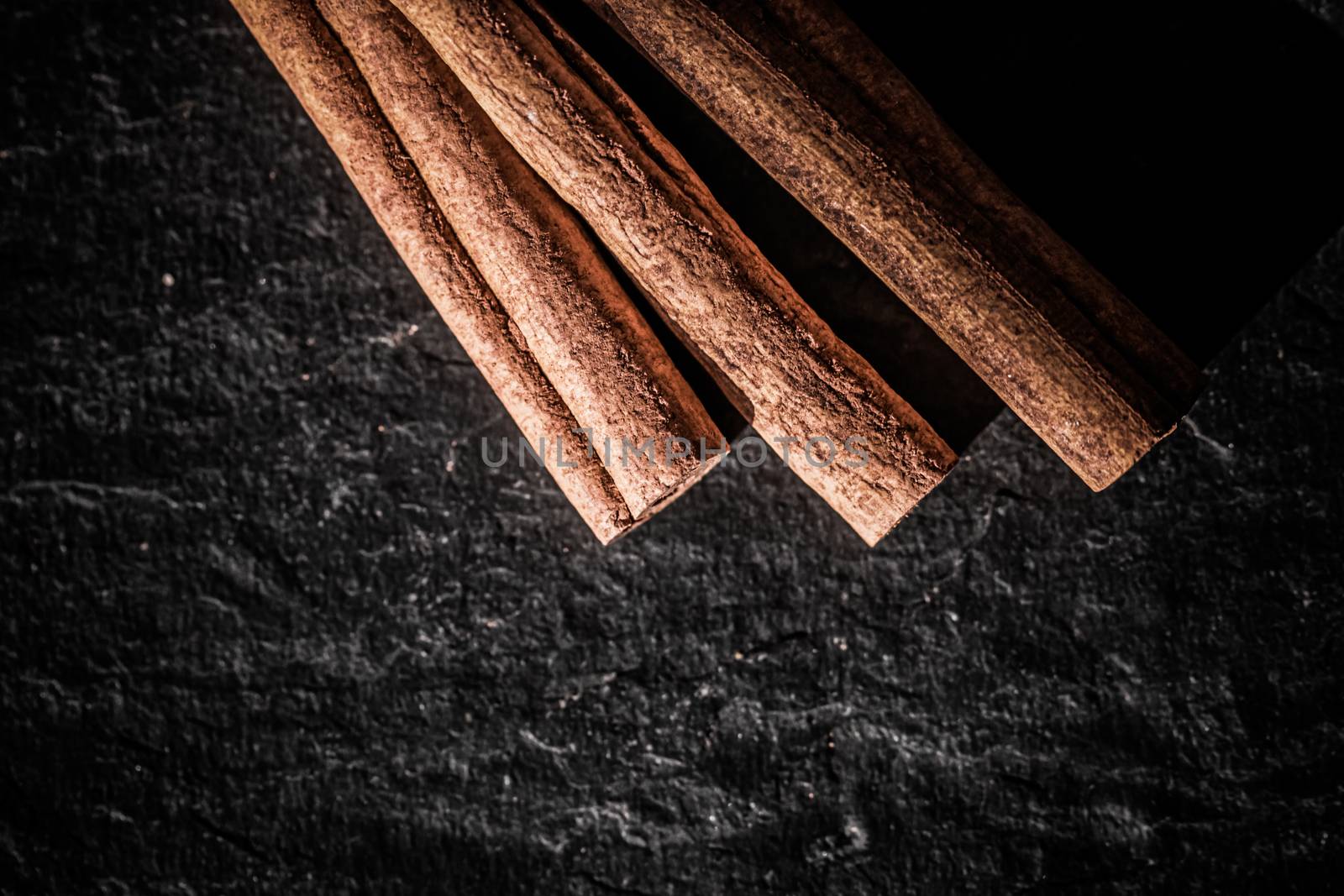 Cinnamon sticks on black stone background, food recipe by Anneleven