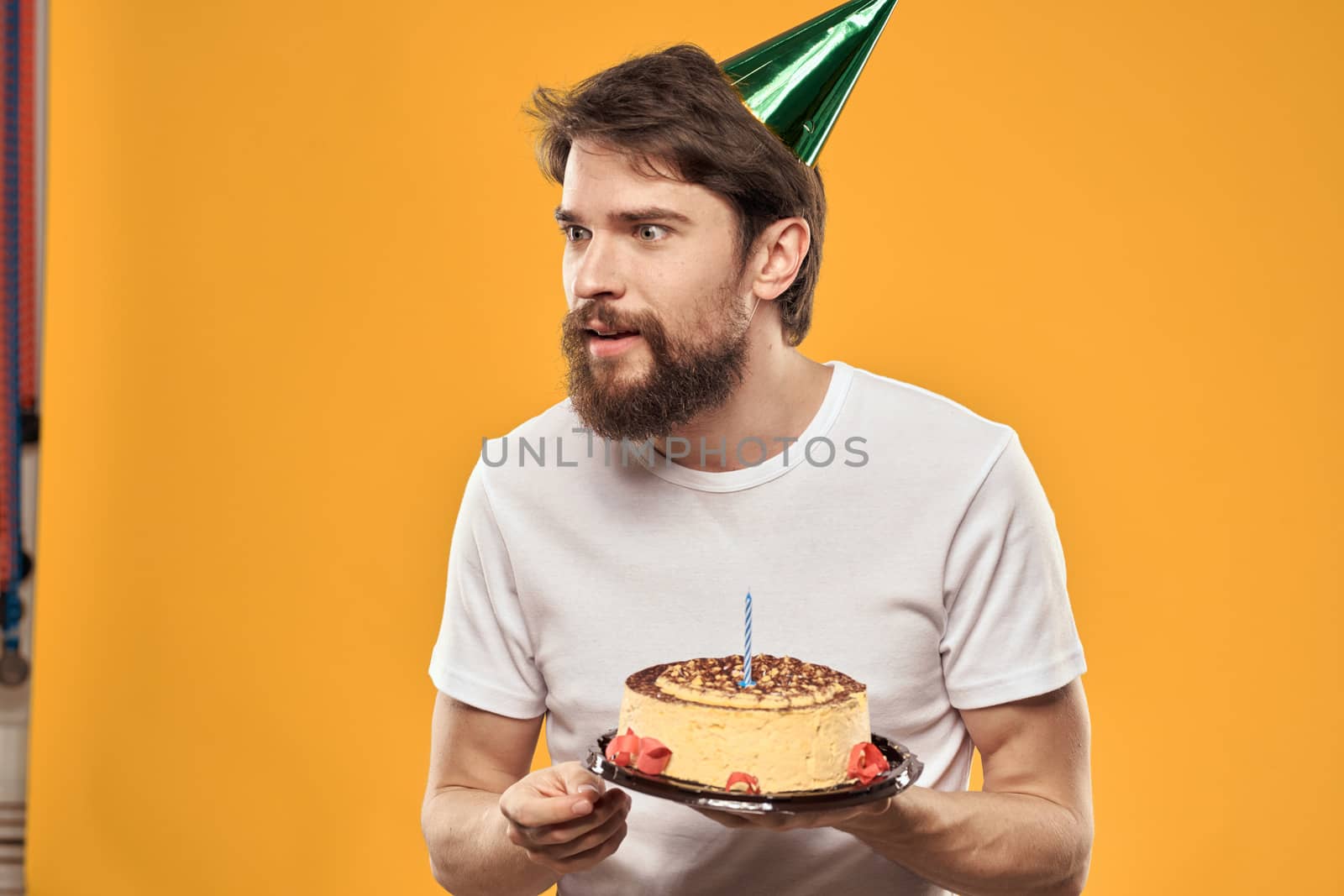 A bearded man with a cake and in a cap celebrating his birthday. High quality photo