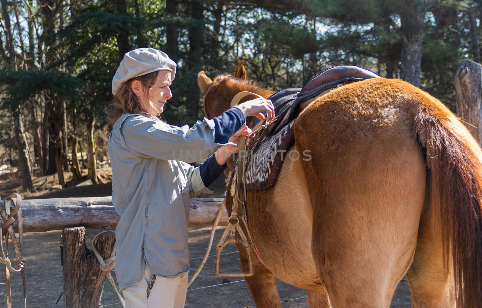 rural woman saddling her horse in the field