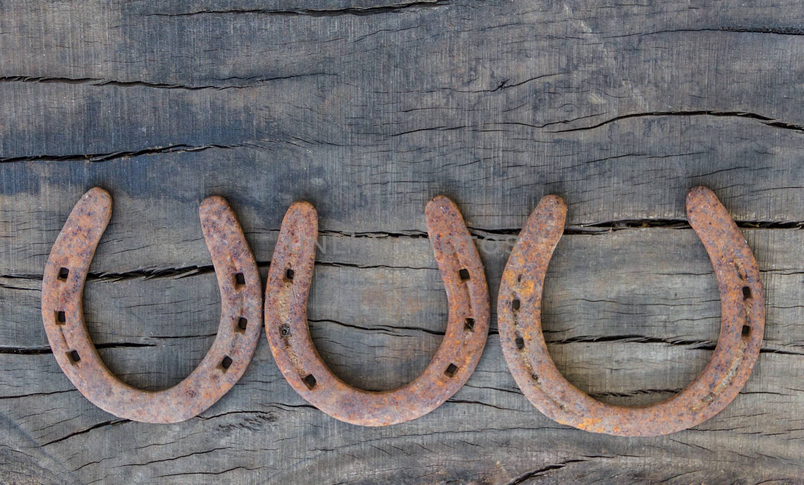 old rusty horseshoes on rustic wood with place for text