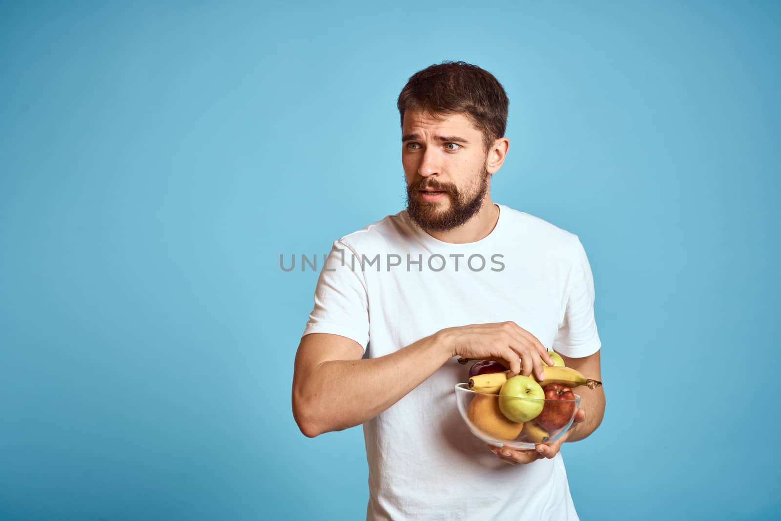 dark background handsome man with a beard holding fresh fruit and lifestyle transparent cup by SHOTPRIME