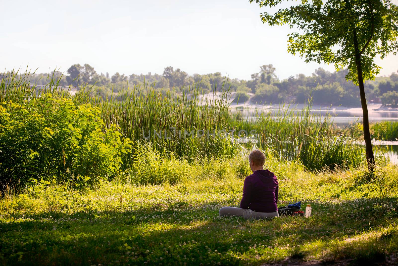 A woman is meditating, in front of the river in the morning by MaxalTamor