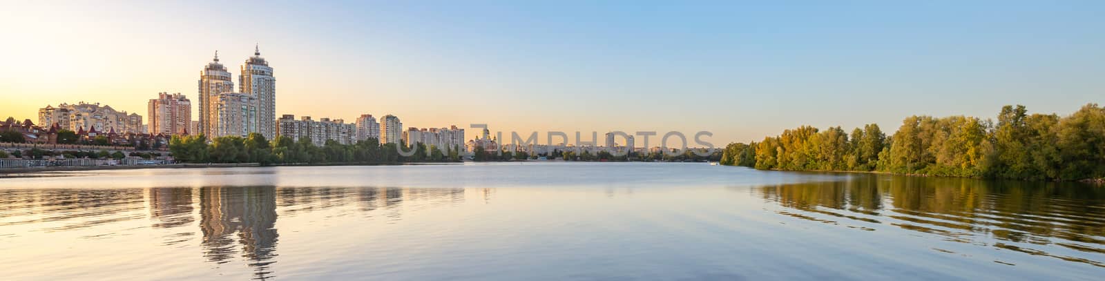 Panoramic view oth the high Obolon buildings near the Dnieper river in Kiev, Ukraine. Blue clear sky and reflection in the water.