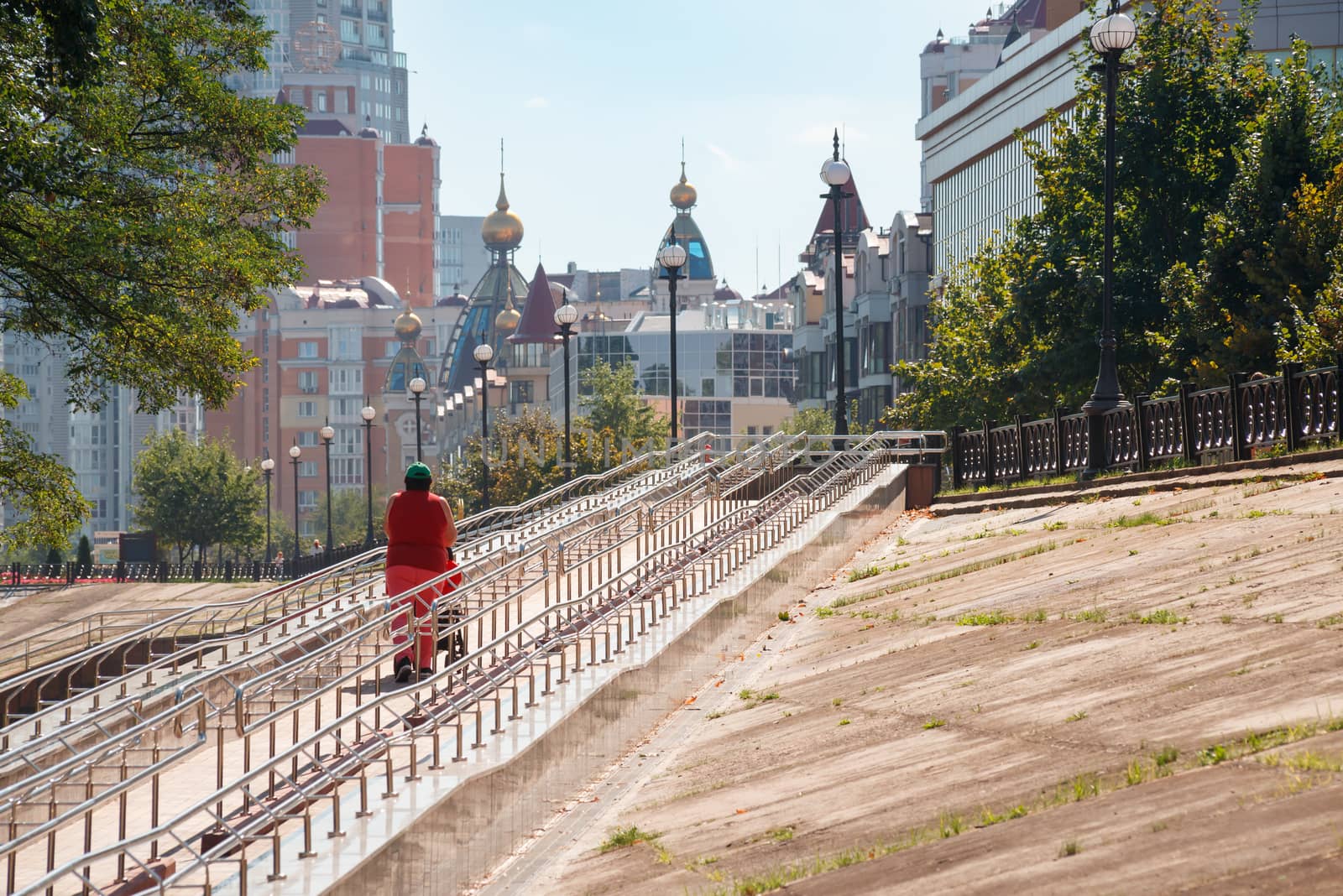 A woman with a stroller climbs a long metal ramp  by MaxalTamor