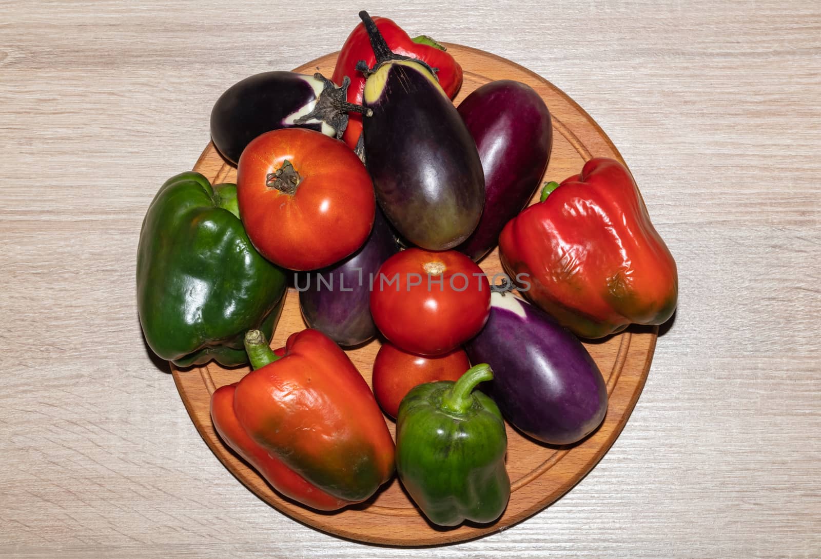 A top close-up shot of various vegetables lying on a wooden cooking board. Isolated on wooden background.