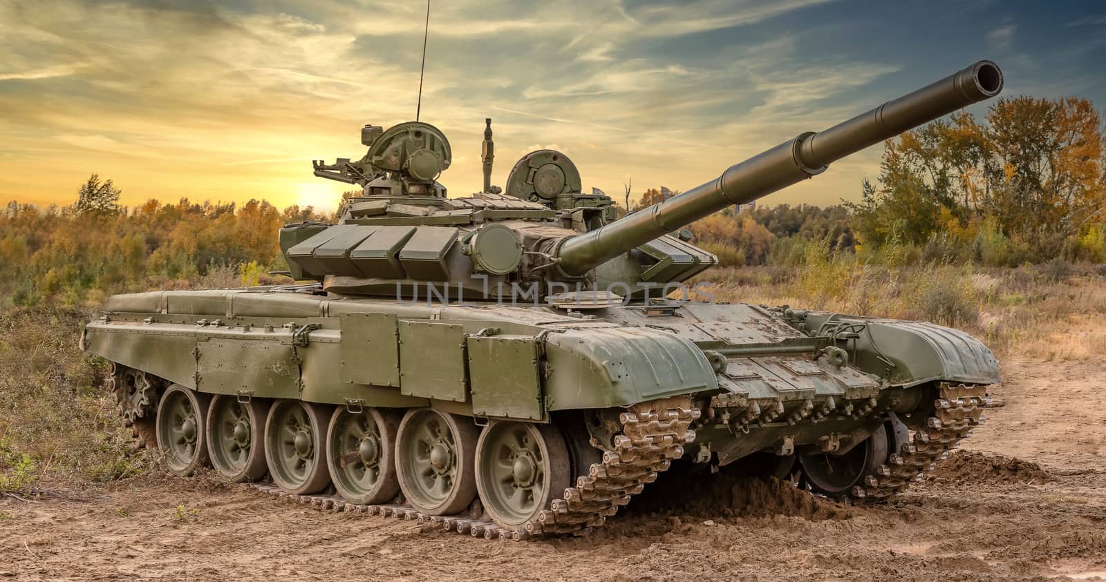 A side shot of russian tank T-64 in the field. Beautiful sunset sky as a background.