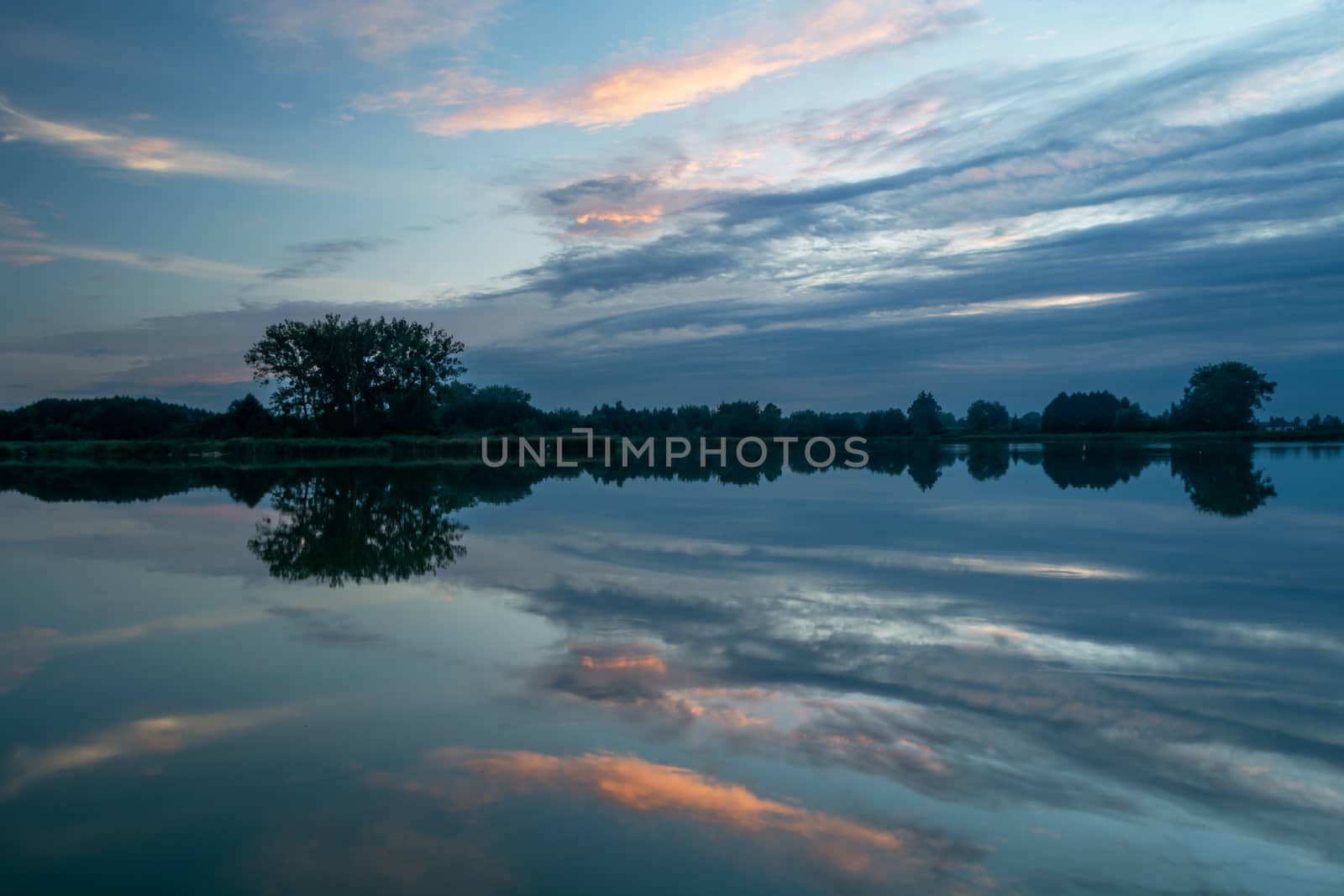 Mirroring of the evening clouds in the lake water, summer view