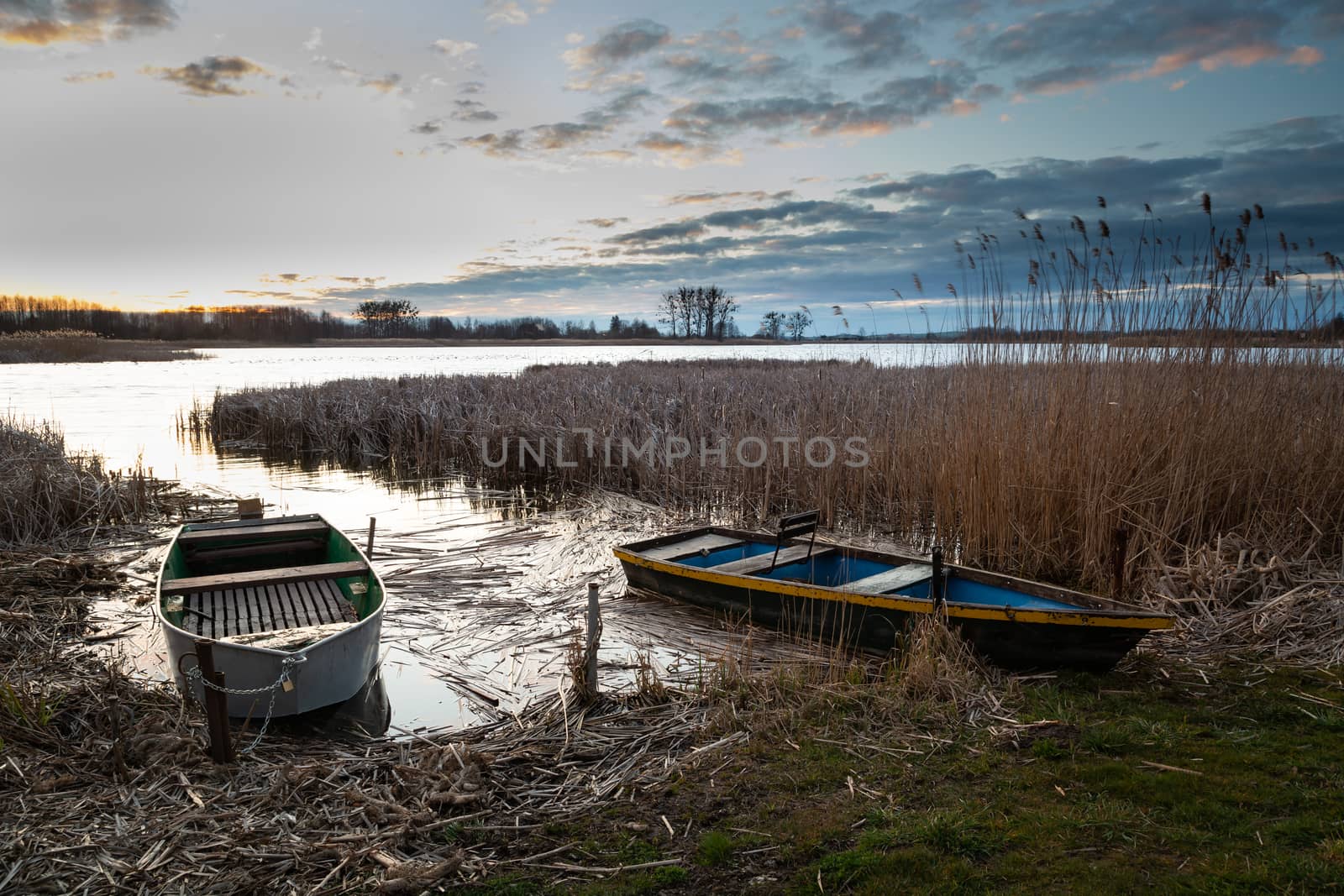 Fishing boats on the lake shore and evening clouds, spring view