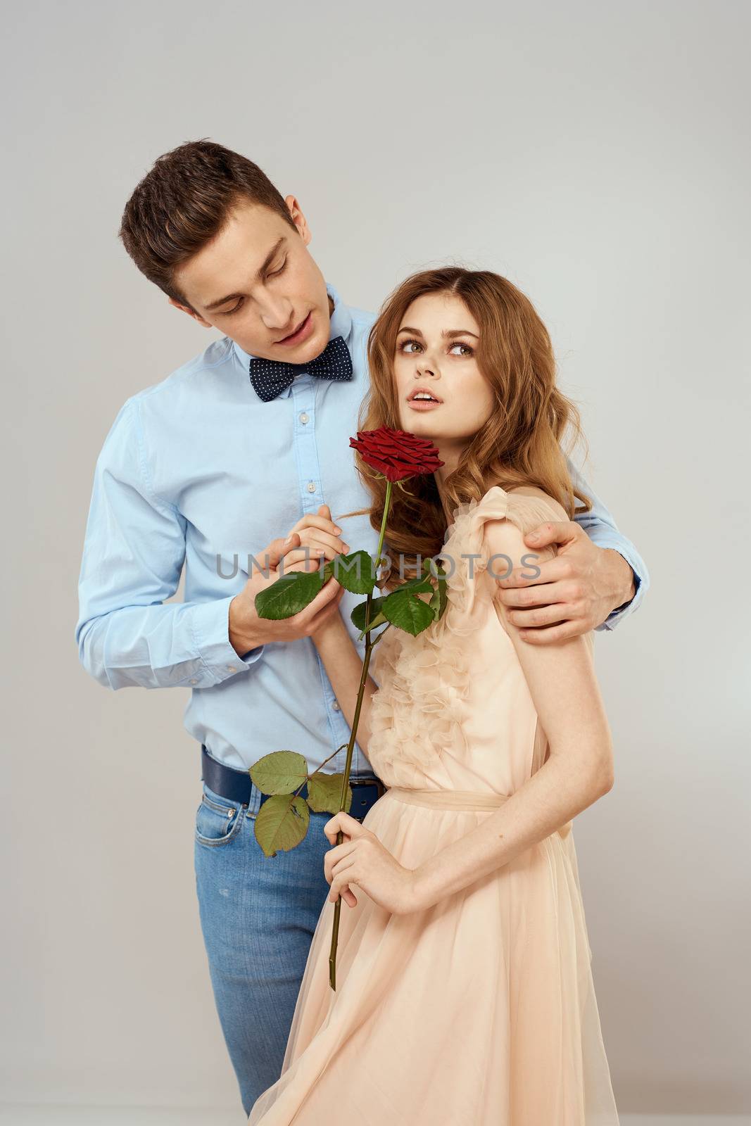 Young couple romance hug relationship dating red rose light studio background. High quality photo