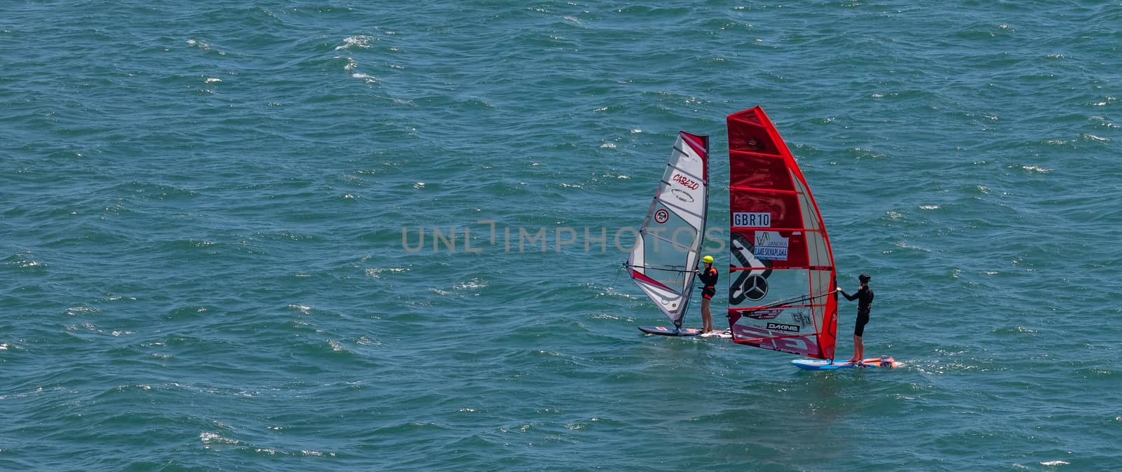 Portland harbour, United Kingdom - July 2, 2020: High Angle aerial panoramic shot of two sail boards with professional surfers on them in Portland harbour.