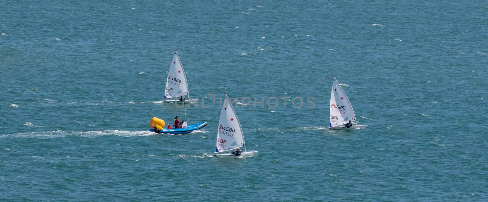 Portland harbour, United Kingdom - July 2, 2020: High Angle aerial panoramic shot of the laser class sailing racing dinghies and a rescue boat in Portland harbour.
