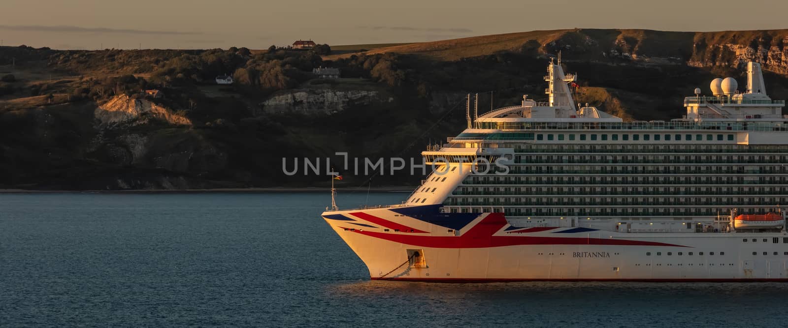 Weymouth Bay, United Kingdom - July 6, 2020: Beautiful panoramic shot of P&O cruise ship Britannia anchored in Weymouth Bay at sunset.