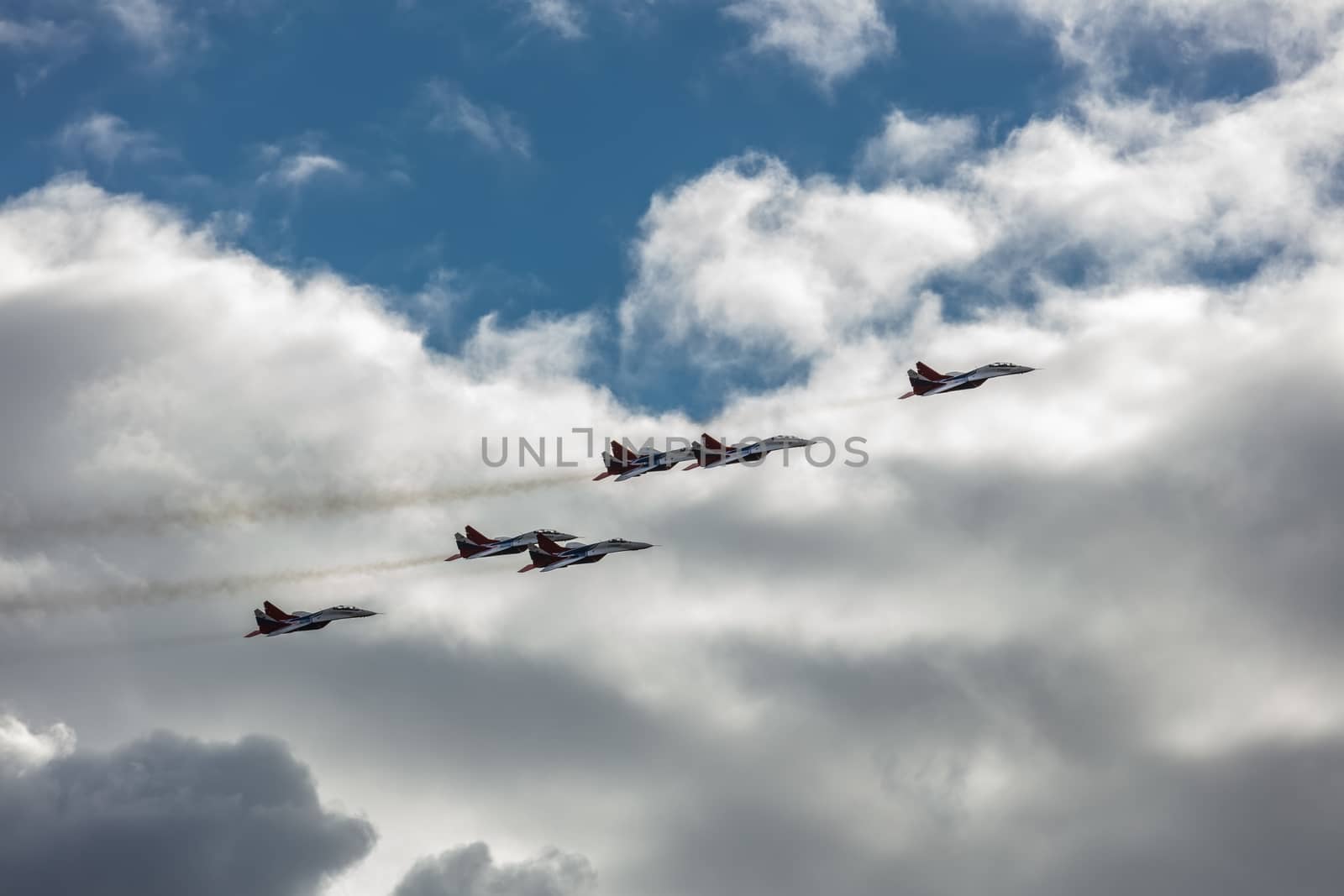 Barnaul, Russia - September 18, 2020: A shot of Strizhi MiG-29 fighter jet squadron performing stunts during an aeroshow. Blue cloudy sky as a background.