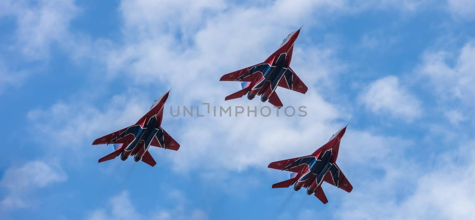 Barnaul, Russia - September 18, 2020: A low angle close-up shot of Strizhi MiG-29 jet squadron performing stunts during an aeroshow. Blue cloudy sky as a background.