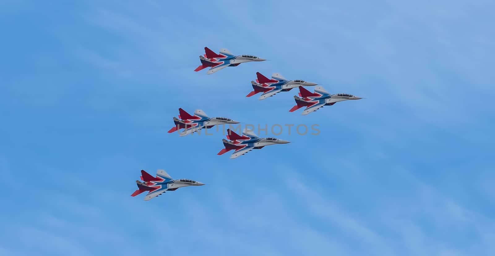 Barnaul, Russia - September 18, 2020: A low angle shot of Strizhi MiG-29 fighter jet squadron performing stunts during an aeroshow. Blue cloudy sky as a background.