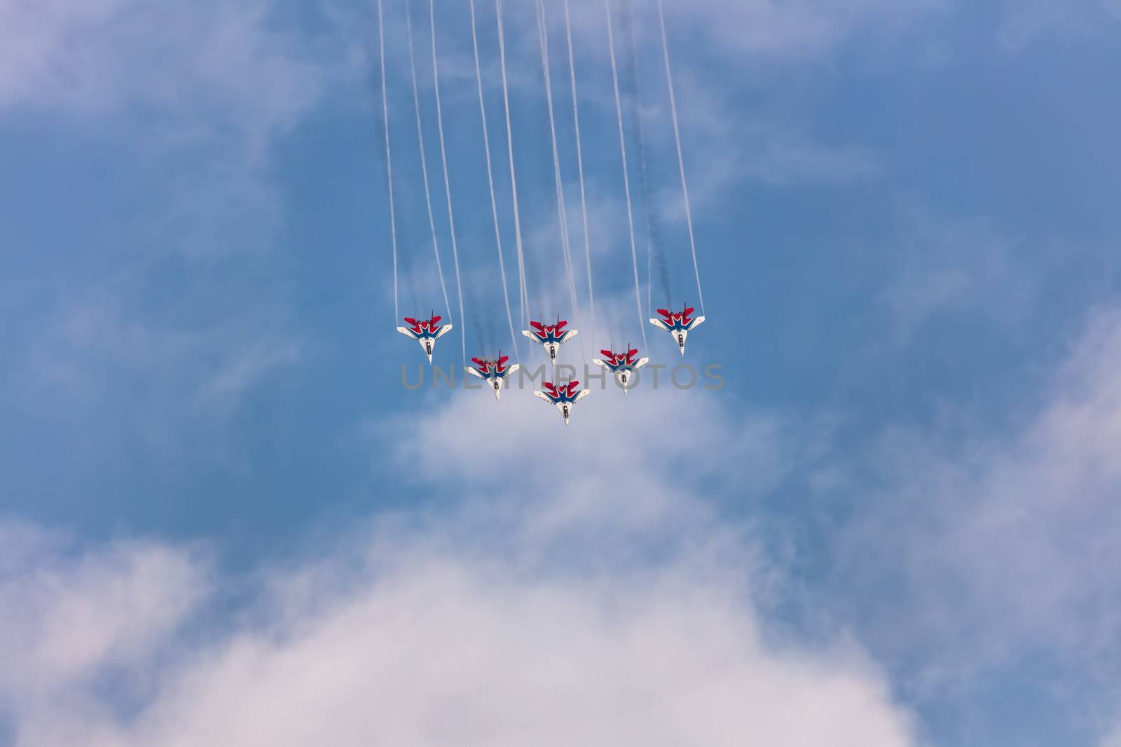 Barnaul, Russia - September 19, 2020: A low angle shot of Strizhi MiG-29 fighter jet squadron performing stunts during an aeroshow. Blue cloudy sky as a background.