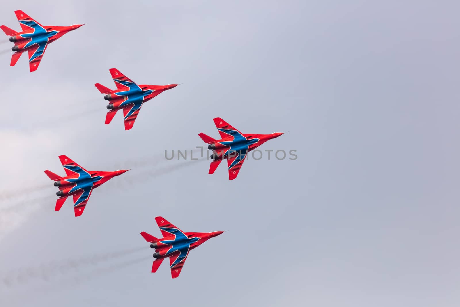 Barnaul, Russia - September 19, 2020: A shot of Strizhi MiG-29 fighter jet squadron performing stunts during an aeroshow. Blue cloudy sky as a background.