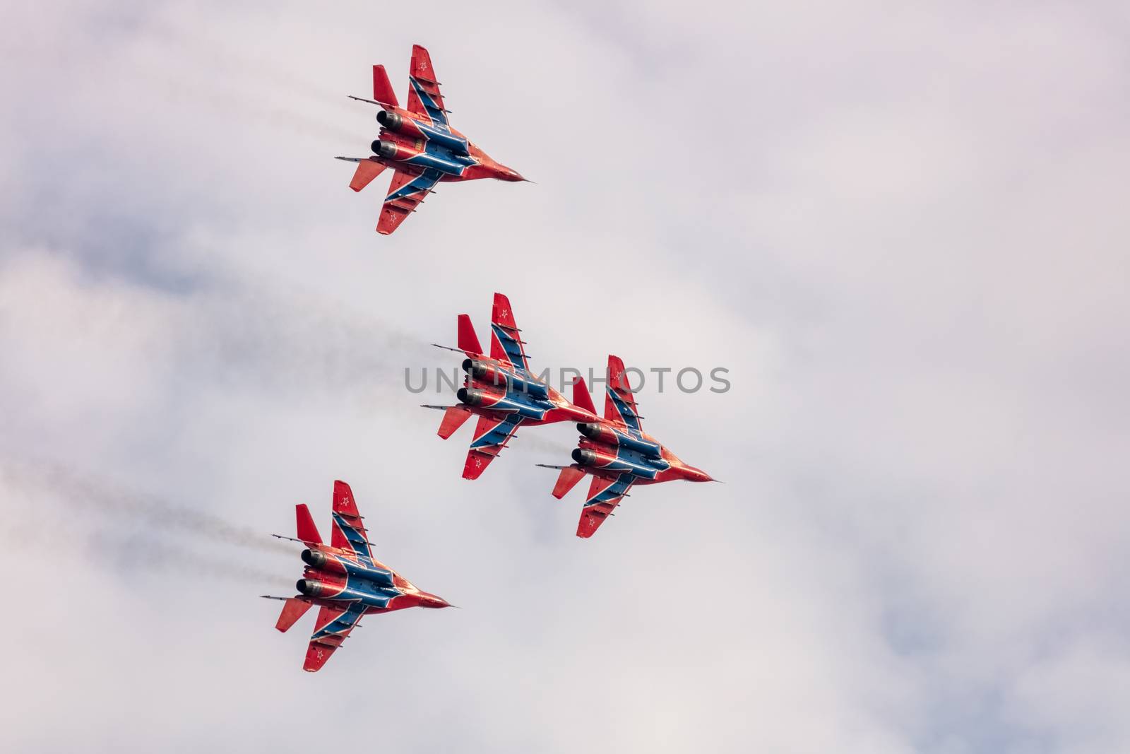 Barnaul, Russia - September 19, 2020: A low angle shot of Strizhi MiG-29 fighter jet squadron performing stunts during an aeroshow. Blue cloudy sky as a background.