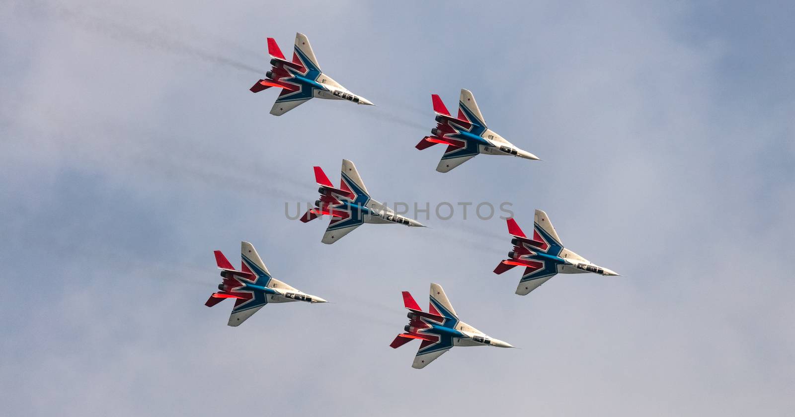 Barnaul, Russia - September 19, 2020: A shot of Strizhi MiG-29 fighter jet squadron performing stunts during an aeroshow. Blue cloudy sky as a background.