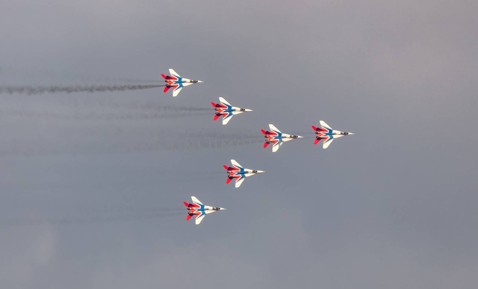Barnaul, Russia - September 19, 2020: A low angle shot of Strizhi MiG-29 fighter jet squadron performing stunts during an aeroshow. Cloudy sky as a background.
