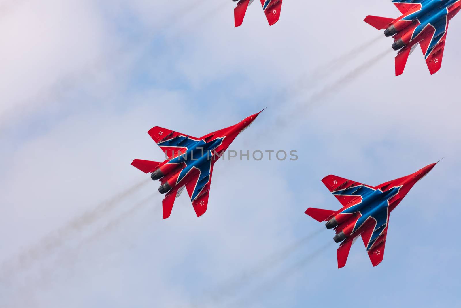 Barnaul, Russia - September 19, 2020: A low angle close-up shot of Strizhi MiG-29 fighter jet squadron performing stunts during an aeroshow. Blue cloudy sky as a background.