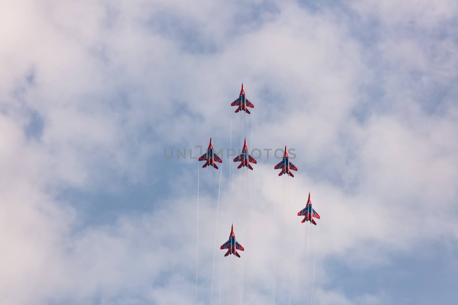 Barnaul, Russia - September 19, 2020: A low angle shot of Strizhi MiG-29 fighter jet squadron performing vertical ascending during an aeroshow. Blue cloudy sky as a background.