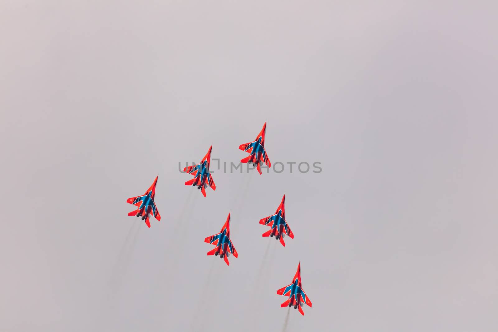 Barnaul, Russia - September 19, 2020: A low angle shot of Strizhi MiG-29 fighter jet squadron performing vertical ascending during an aeroshow. Blue cloudy sky as a background.