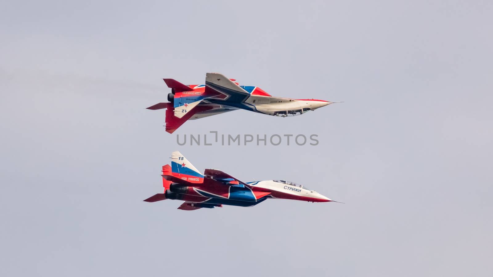 Barnaul, Russia - September 19, 2020: A low angle close-up shot of Strizhi MiG-29 fighter jets flying symmetrically with one of the fighter jets flying above the other during an aeroshow