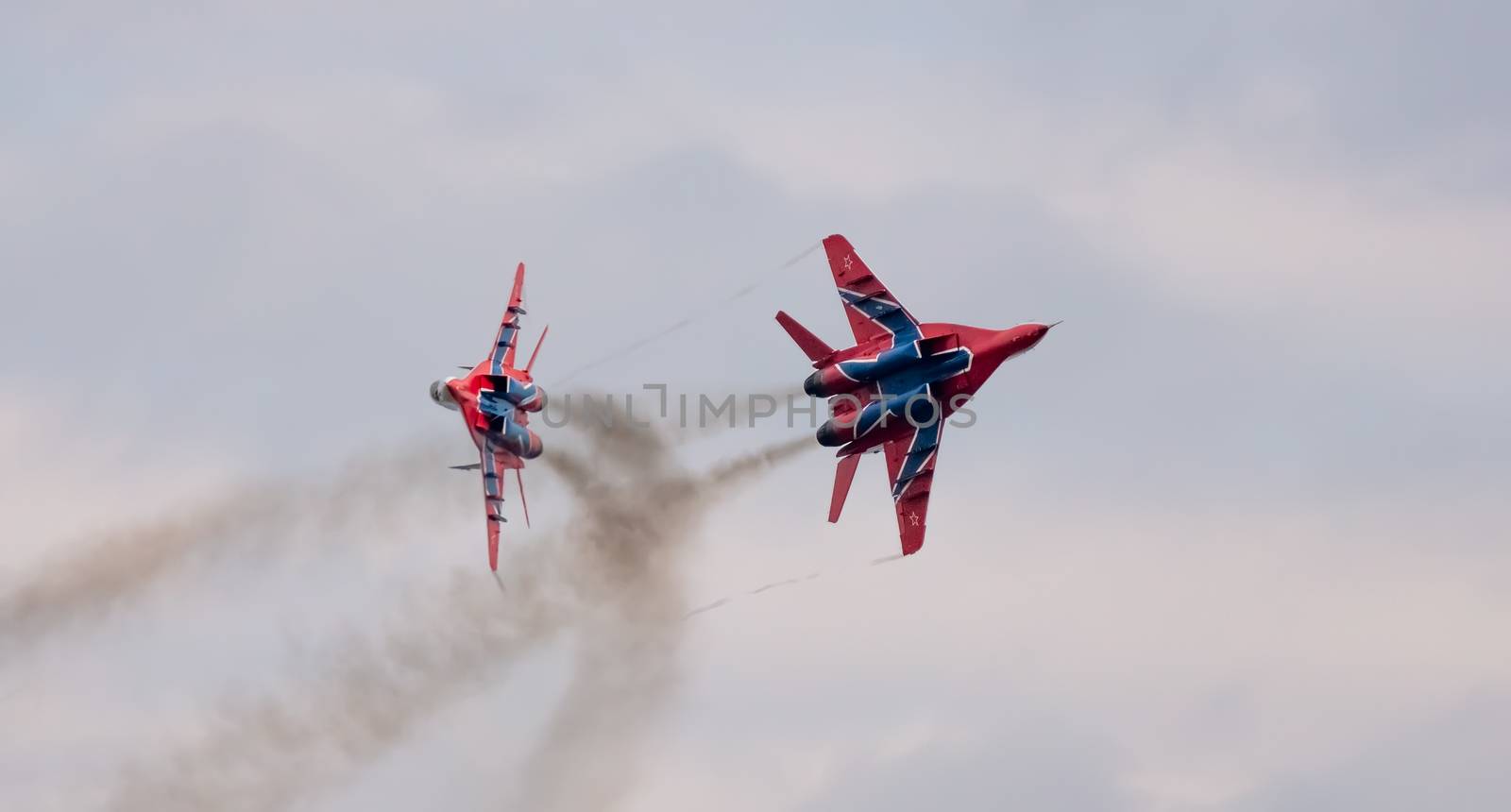 Barnaul, Russia - September 19, 2020: A low angle close-up shot of Strizhi MiG-29 fighter jet performing stunts during an aeroshow. White cloudy sky as a background.