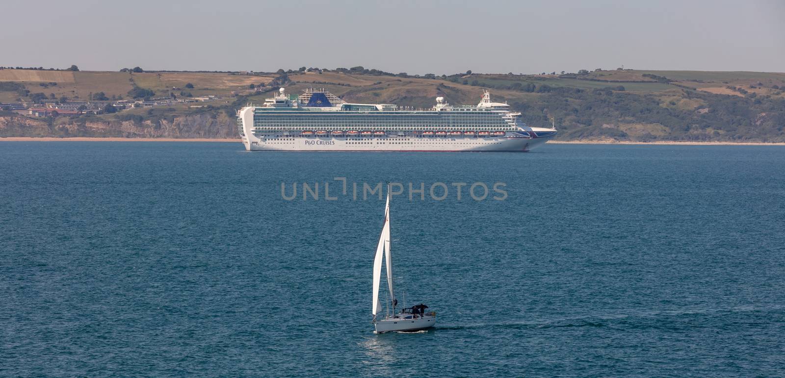 Weymouth Bay, United Kingdom - June 25, 2020: Beautiful panoramic shot of P&O cruise ship Ventura anchored in Weymouth Bay. Sail boat moving in the foreground.