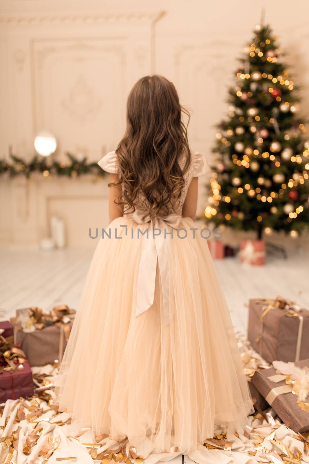 Beautiful little girl posing near the Christmas tree.