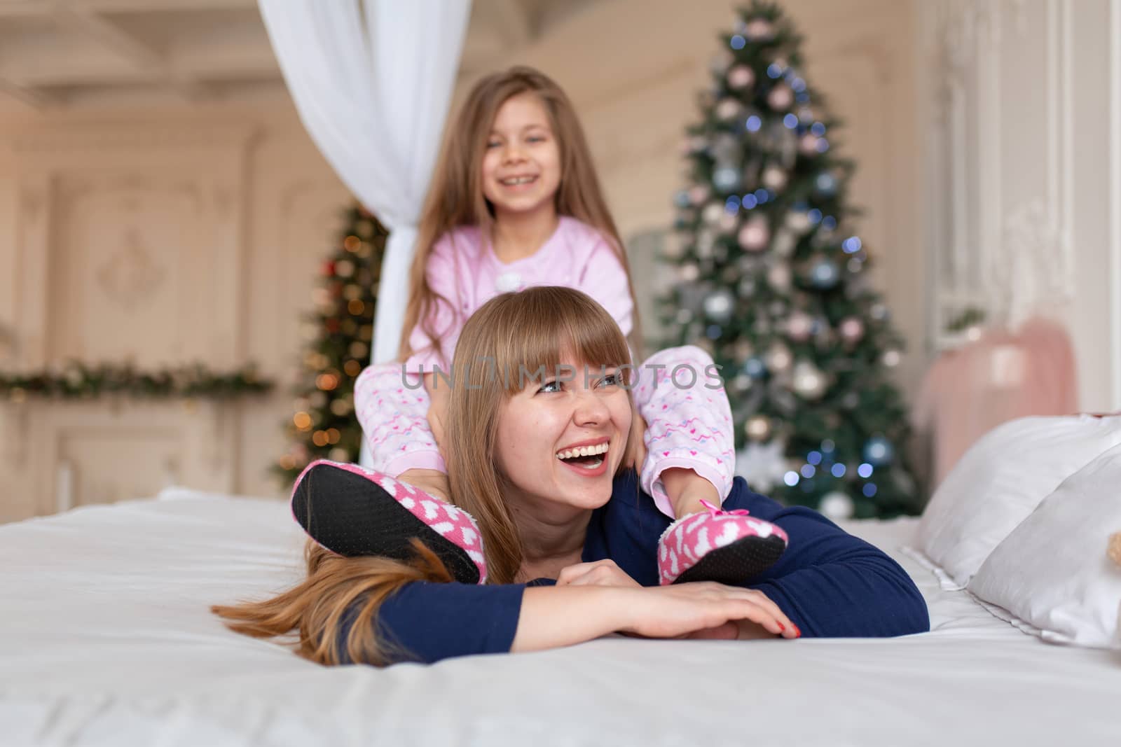 Little girl spends time playing with mom while lying in bed. Christmas tale. Happy childhood by Try_my_best