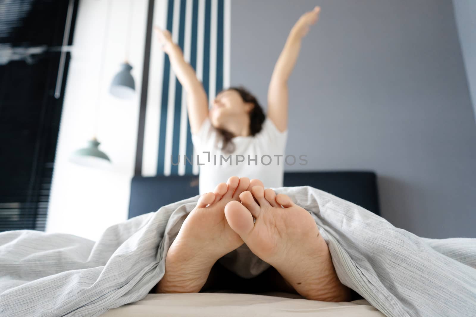 Beautiful girl wakes up in a good mood in a stylish apartment. View from the feet.