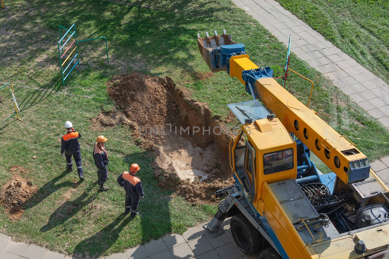 Minsk, Belarus - 11 September 2018: a team of workers and an excavator repair a burst heating main