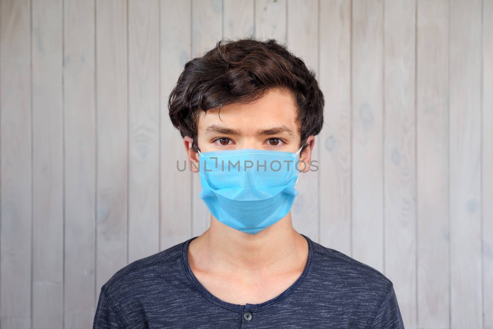 Young man in medical facemask looking at camera. Coronavirus, covid-19 outbreak. Brown eyes of 15 years old boy in mask. Virus, bacteria, epidemic outbreak. Public health, Safe life during an outbreak by synel