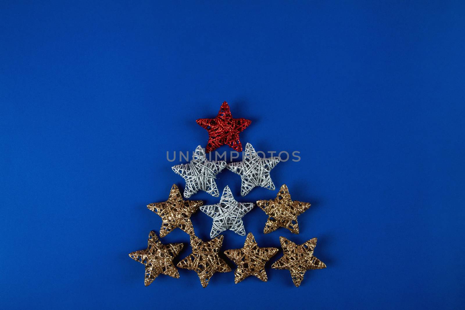 Brilliant red, gold, silver Christmas star on blue background. Use for New Year's greetings. Minimal banner, copy space for text, flatlay.