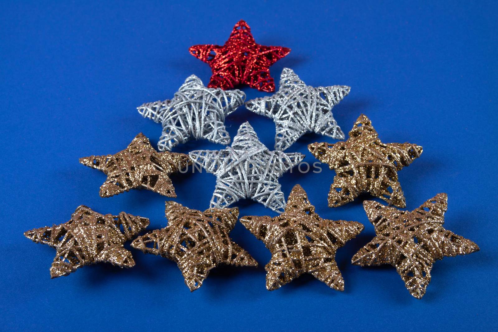 Brilliant red, gold, silver Christmas star on blue background. Use for New Year's greetings. Minimal banner, copy space for text, flatlay.