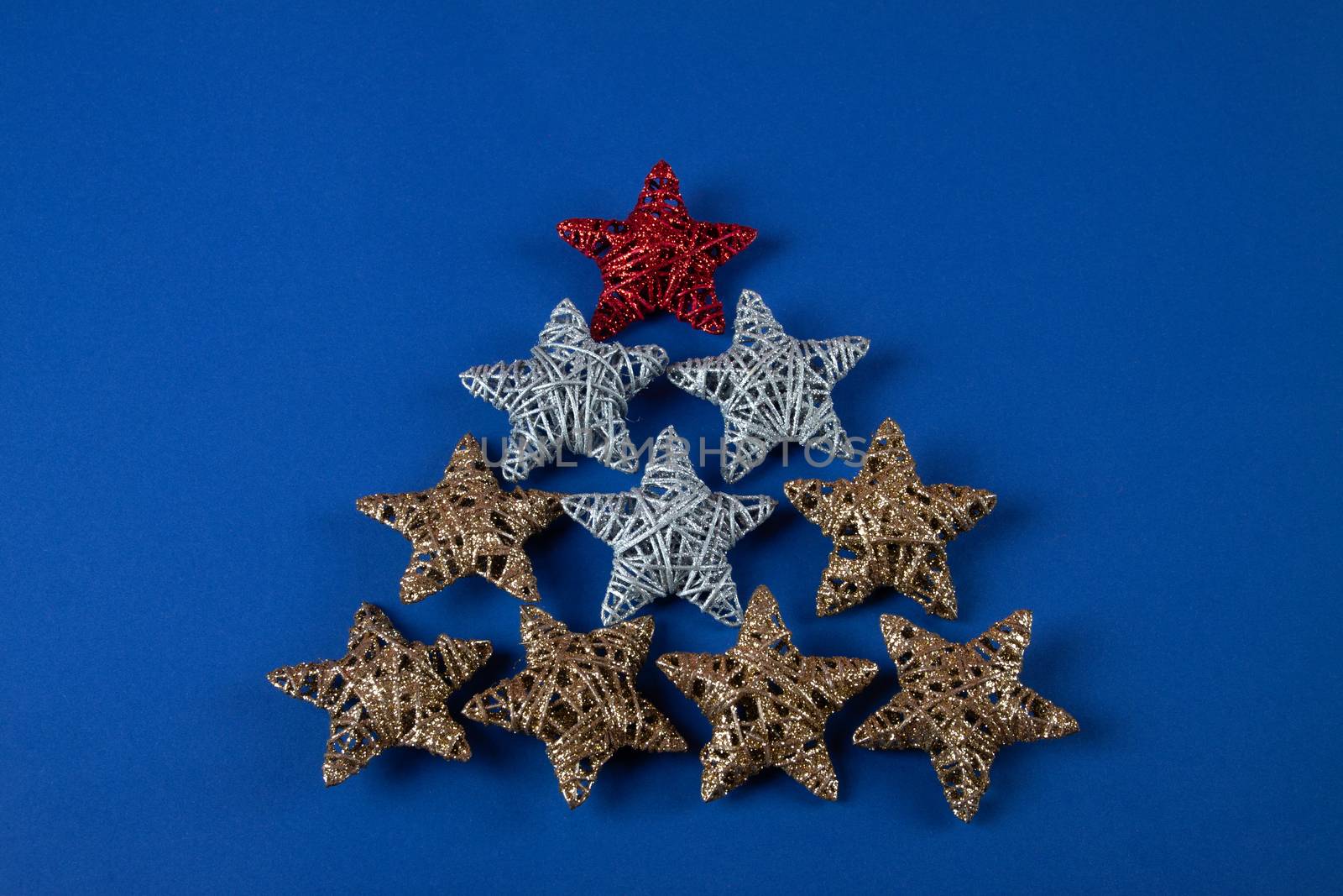 Brilliant red, gold, silver Christmas star on blue background. Use for New Year's greetings. Minimal banner, copy space for text, flatlay.