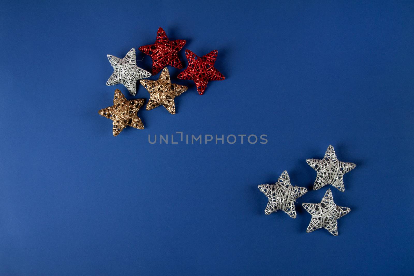 Brilliant red, gold, silver Christmas star on blue background. Use for New Year's greetings. Minimal banner, copy space for text, flatlay.