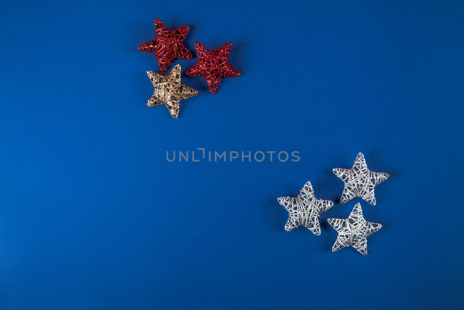 Brilliant red, gold, silver Christmas star on blue background. Use for New Year's greetings. Minimal banner, copy space for text, flatlay.