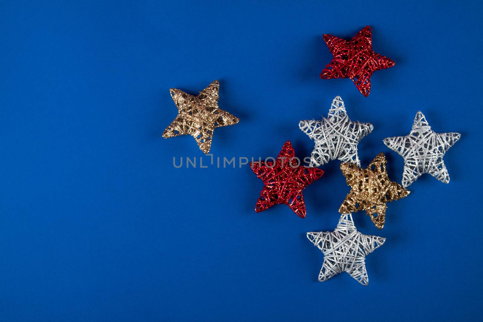 Brilliant red, gold, silver Christmas star on blue background. Use for New Year's greetings. Minimal banner, copy space for text, flatlay.