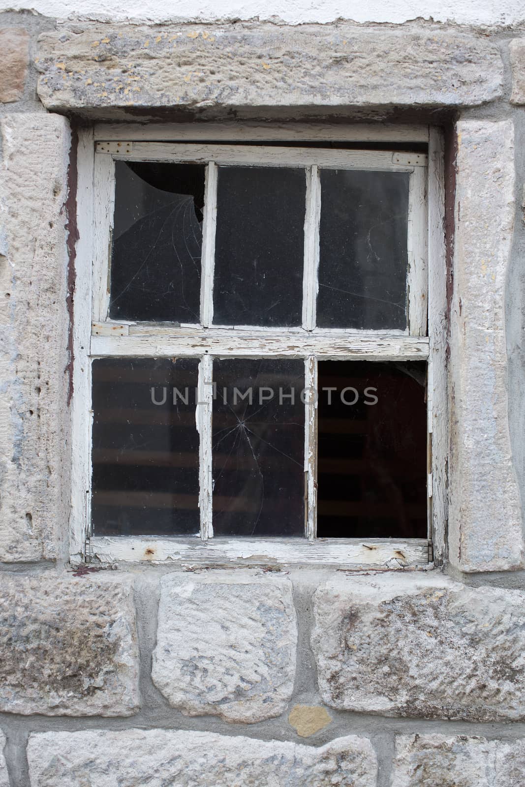 Old weathered window in a massive stone wall