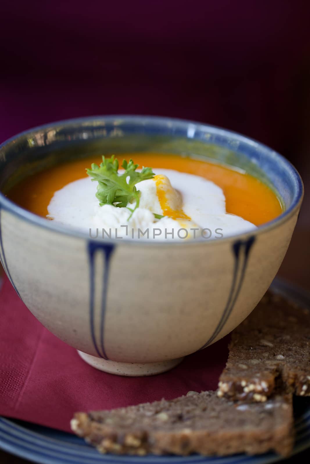 Small bowl filled with tasty carrot soup with slices of brown bread