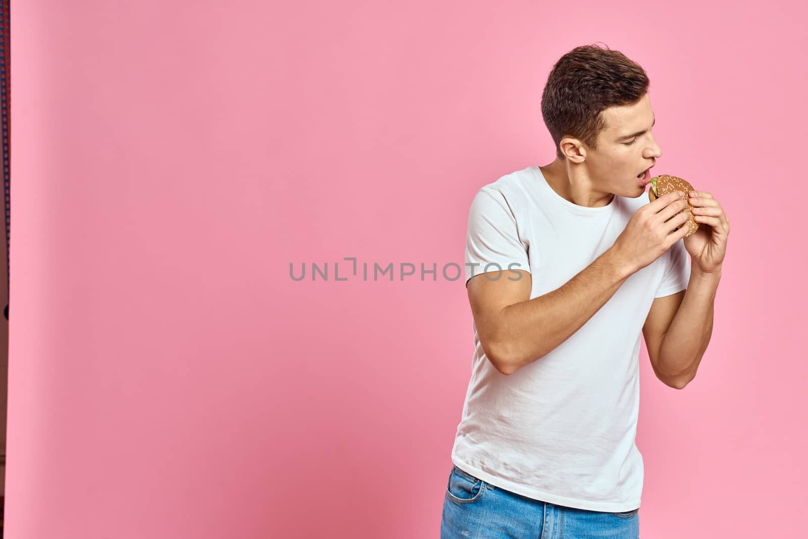 man with big hamburger on pink background calories fast food cropped view Copy Space close-up by SHOTPRIME