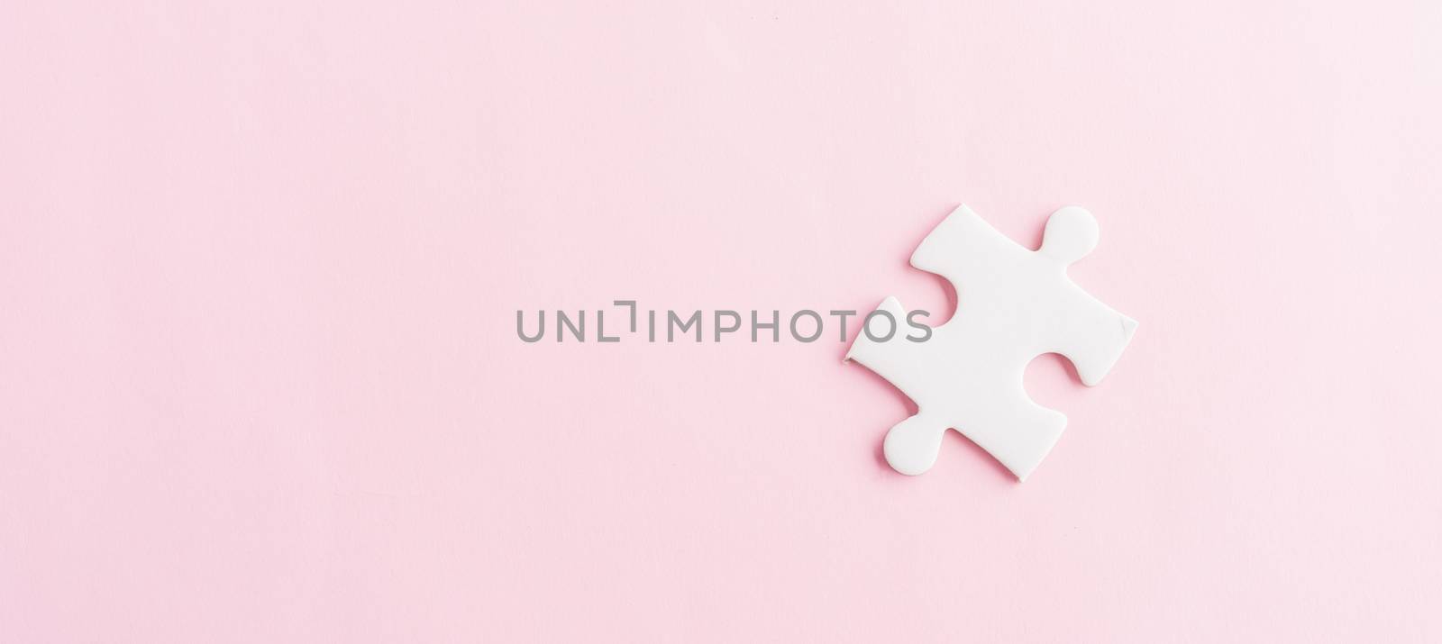 Top view flat lay of one paper plain white jigsaw puzzle game last pieces for solve, studio shot on a pink background, quiz calculation concept